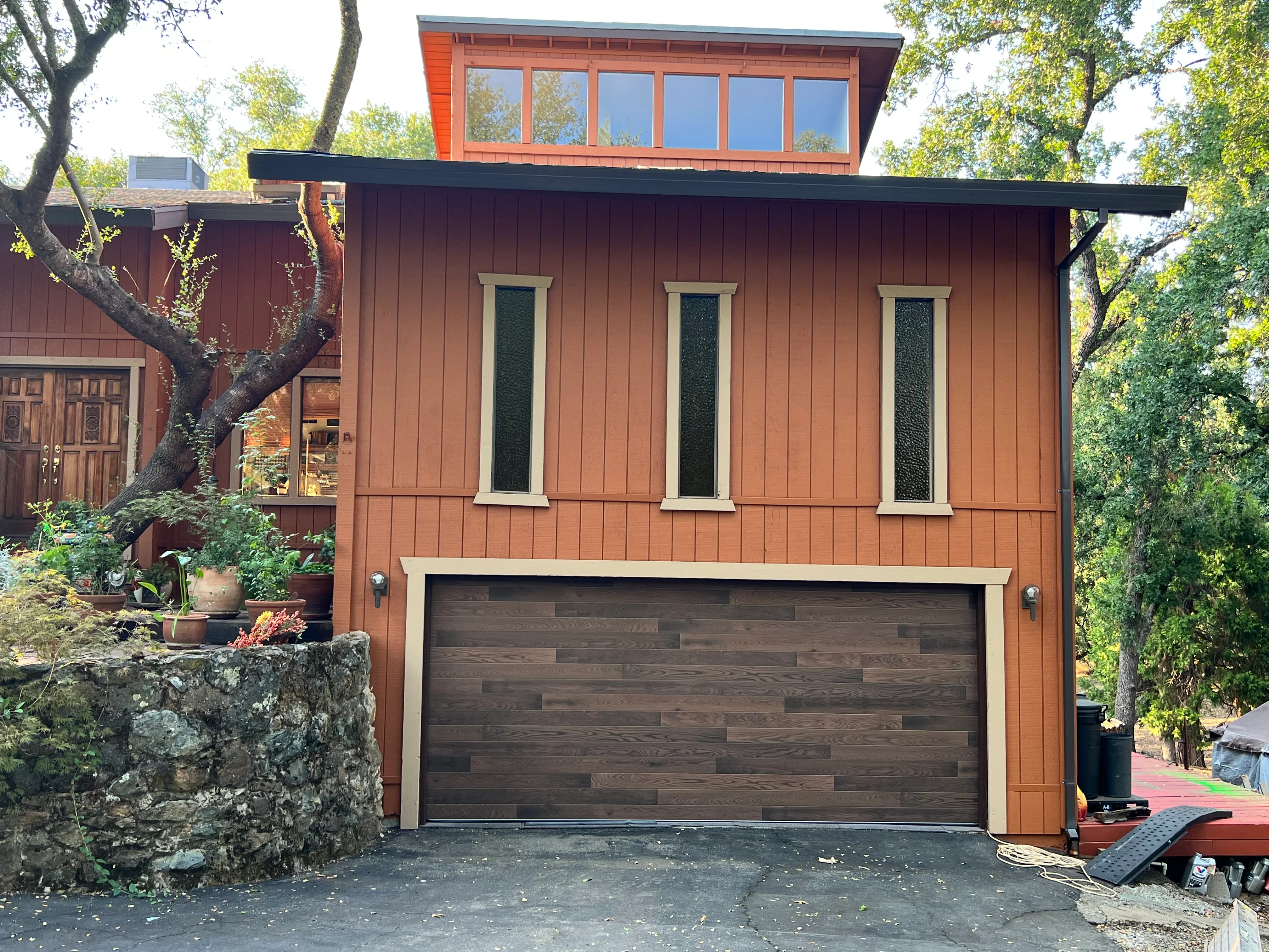 Terracotta painted home exterior with cream trim, dark garage door, and contemporary design