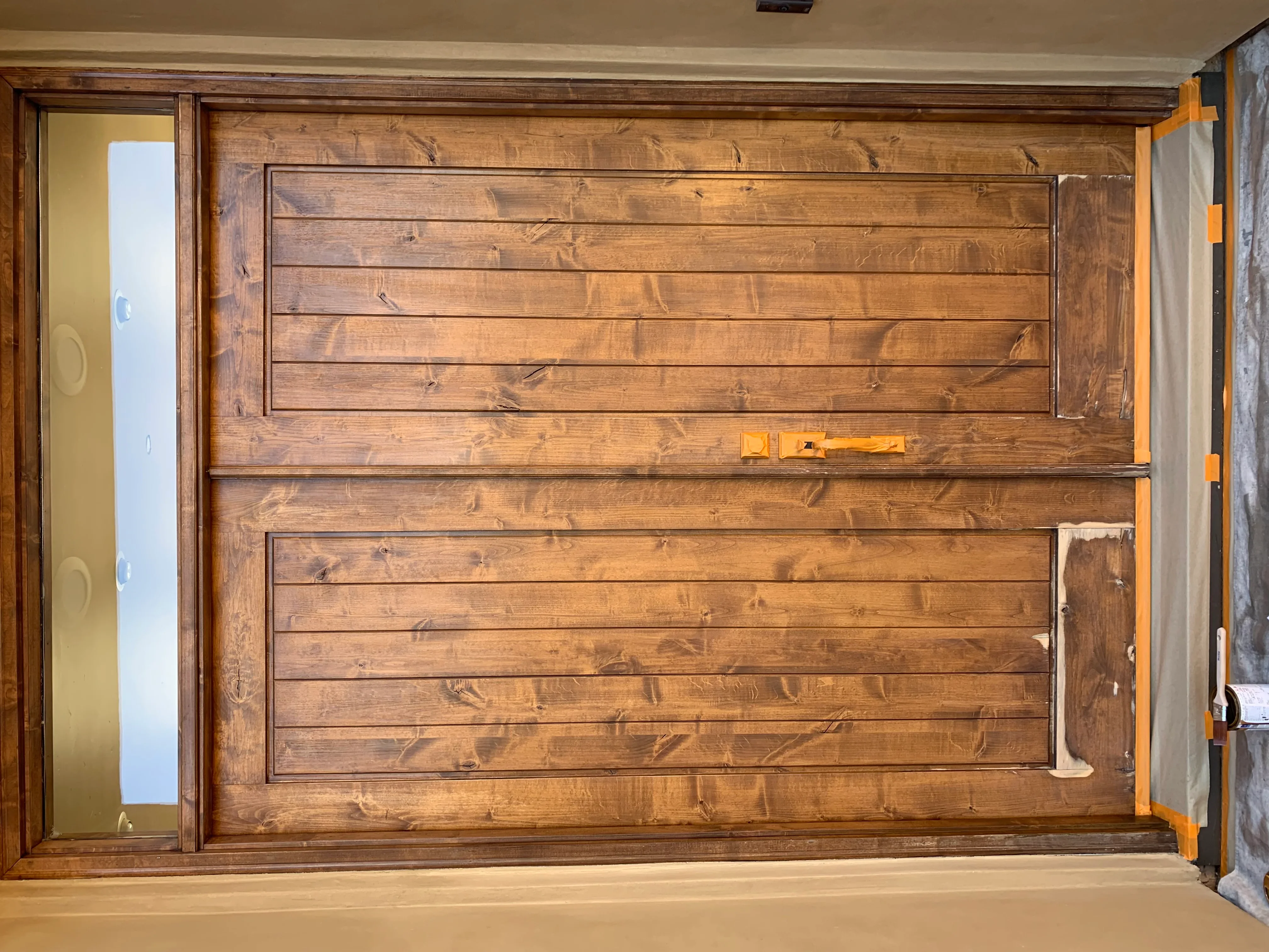 Custom wood garage door with horizontal shiplap panels stained in medium brown finish