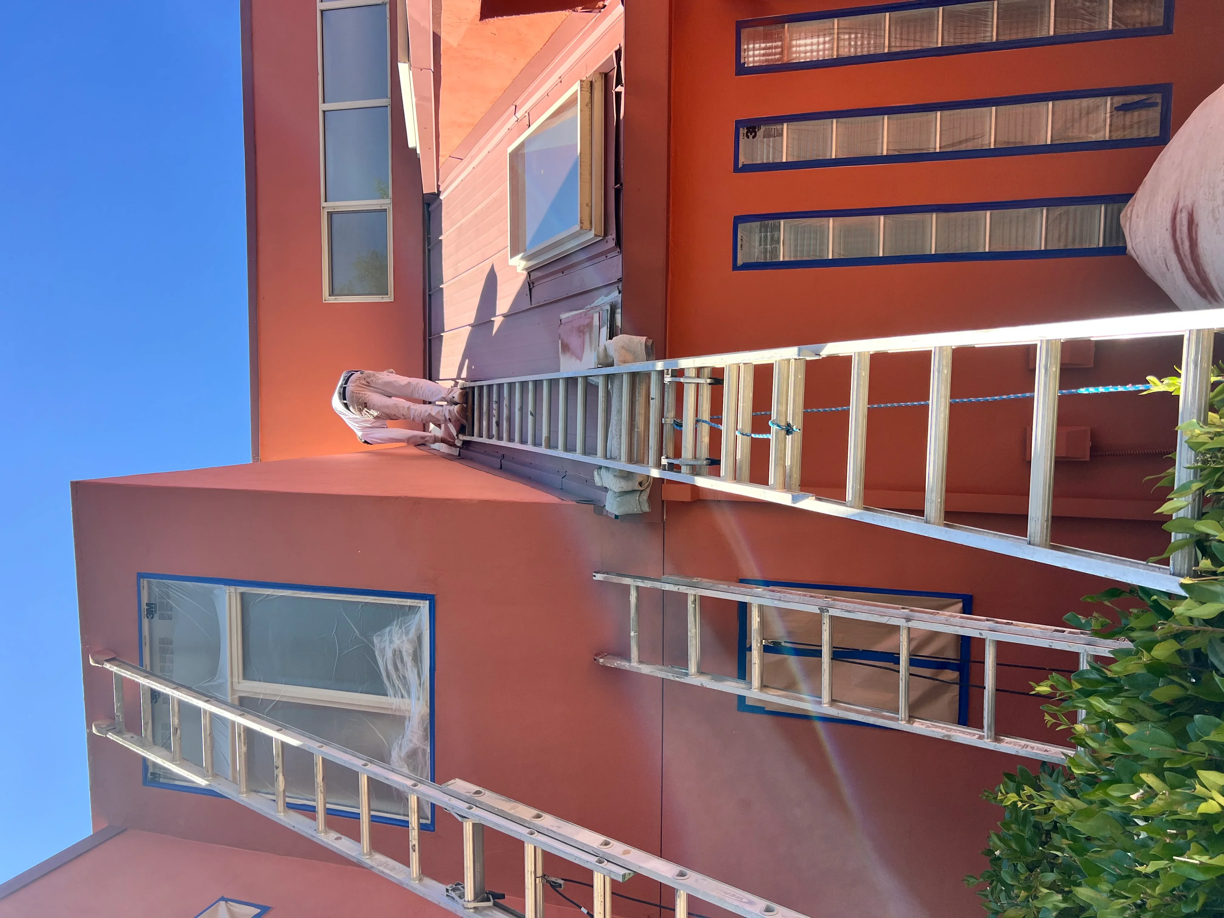 Multi-story rust-orange commercial building with blue-trimmed windows and horizontal railings