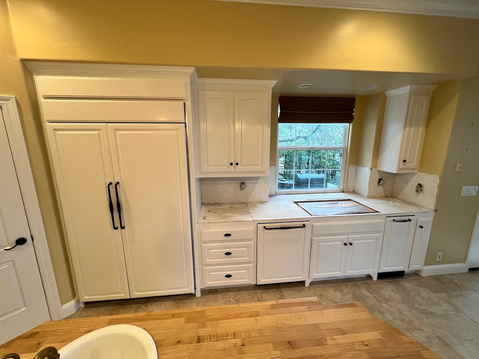 Kitchen with yellow walls, white painted cabinets, and trim work