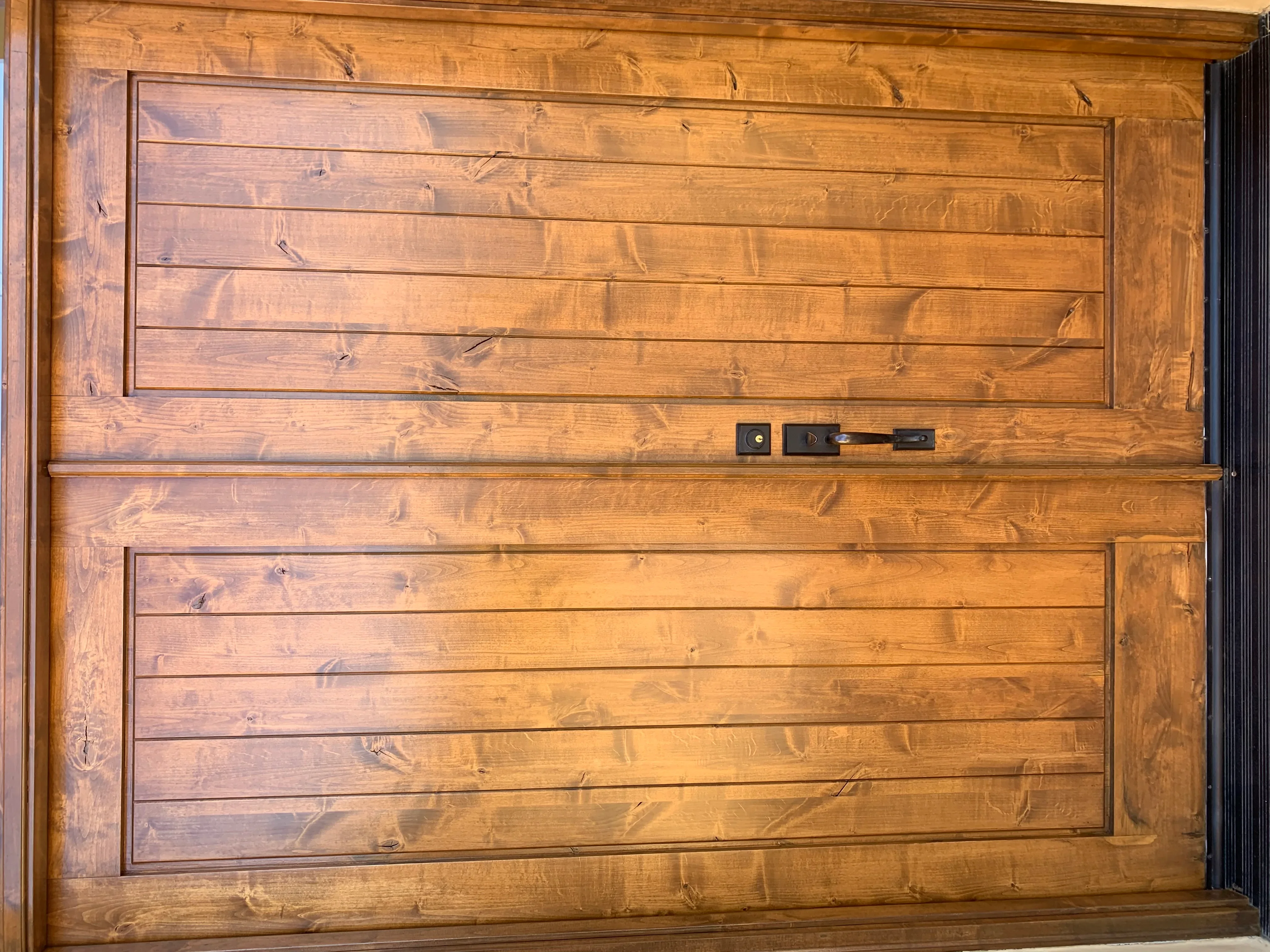 Honey-stained wood garage door with horizontal planks and modern hardware