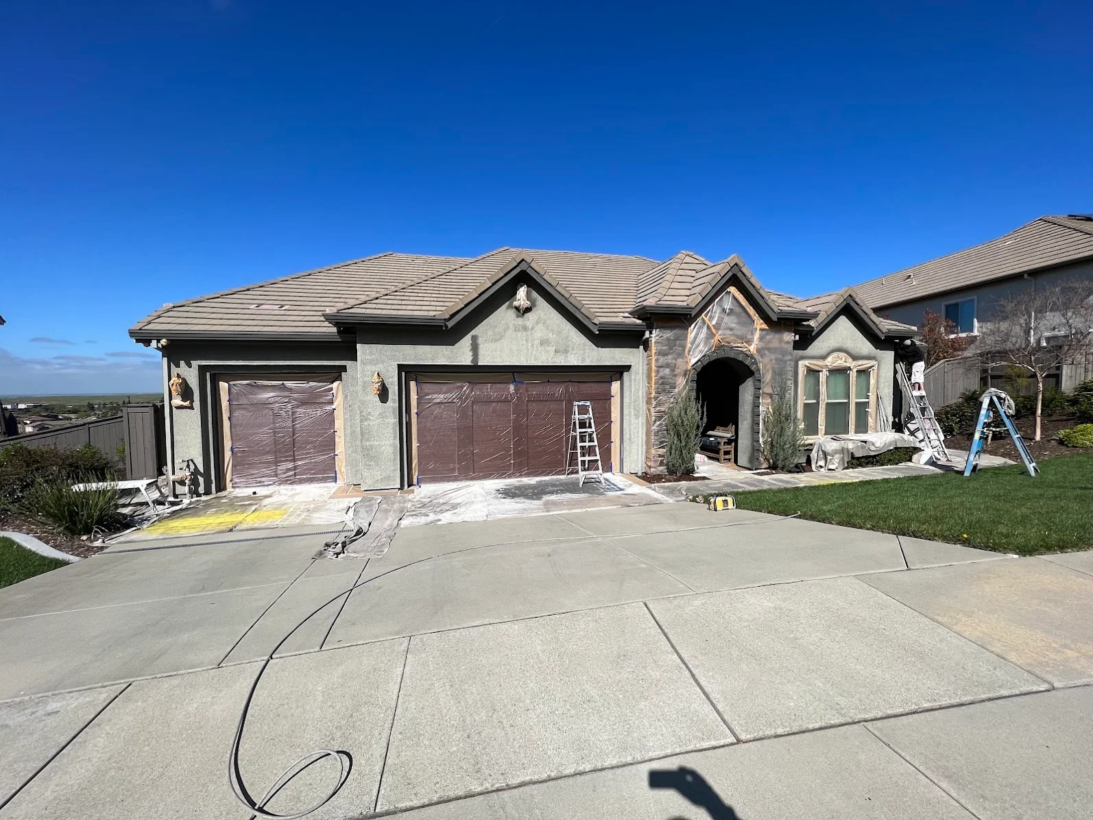 Stucco and stone home exterior with newly primed garage doors and fresh paint preparation