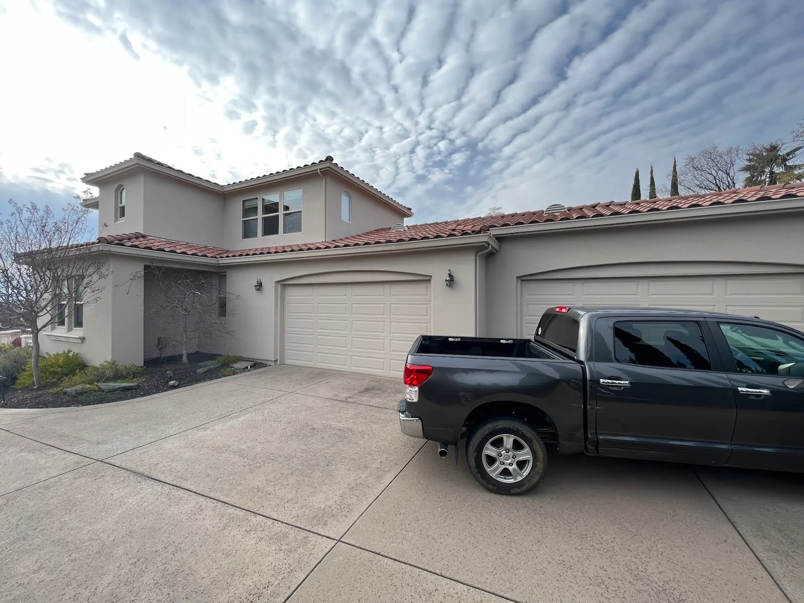 Stucco home exterior with beige paint, clay tile roof, and two-car garage doors