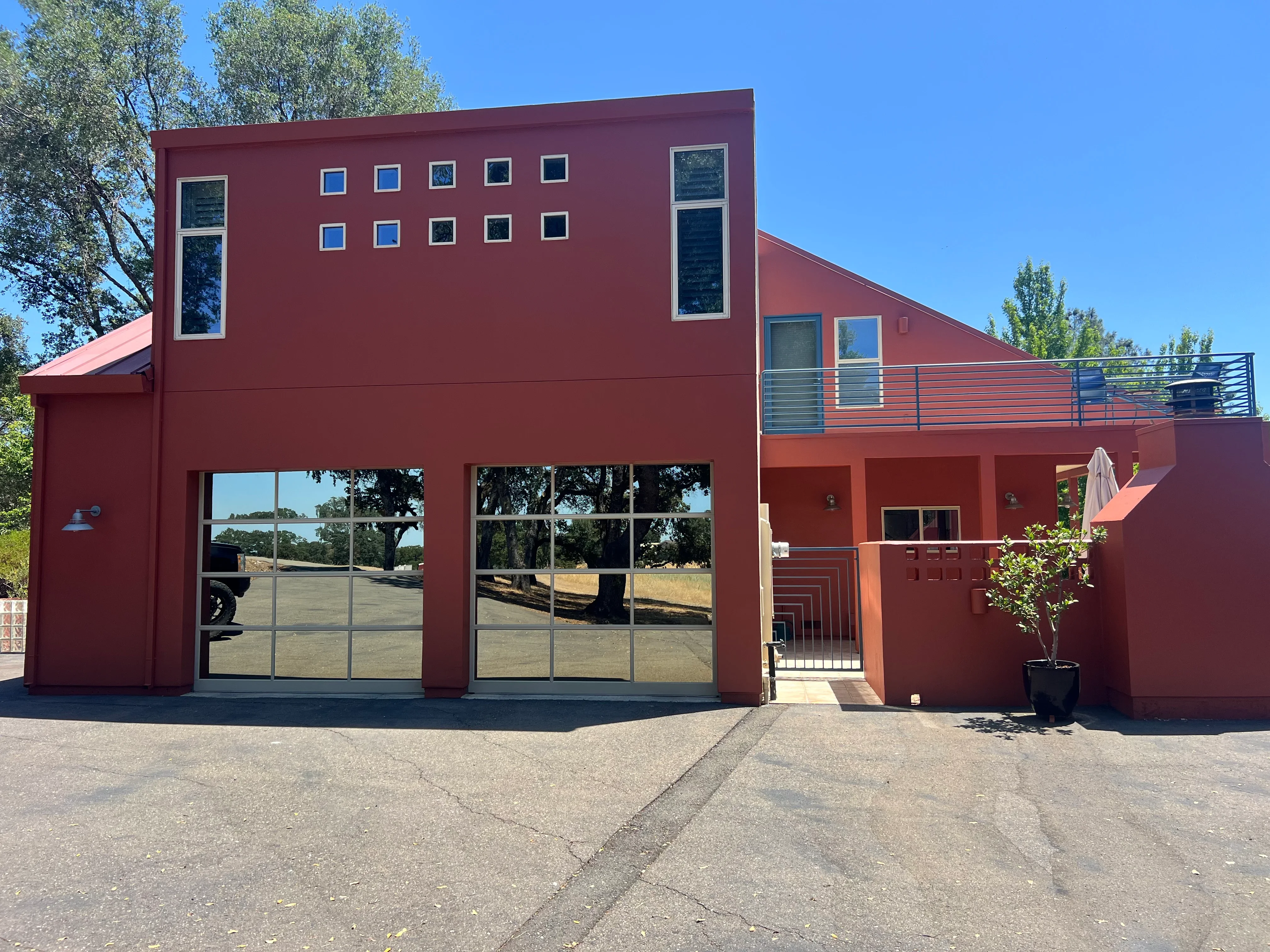 Modern home with burgundy exterior paint, large glass garage doors, and metal deck railing