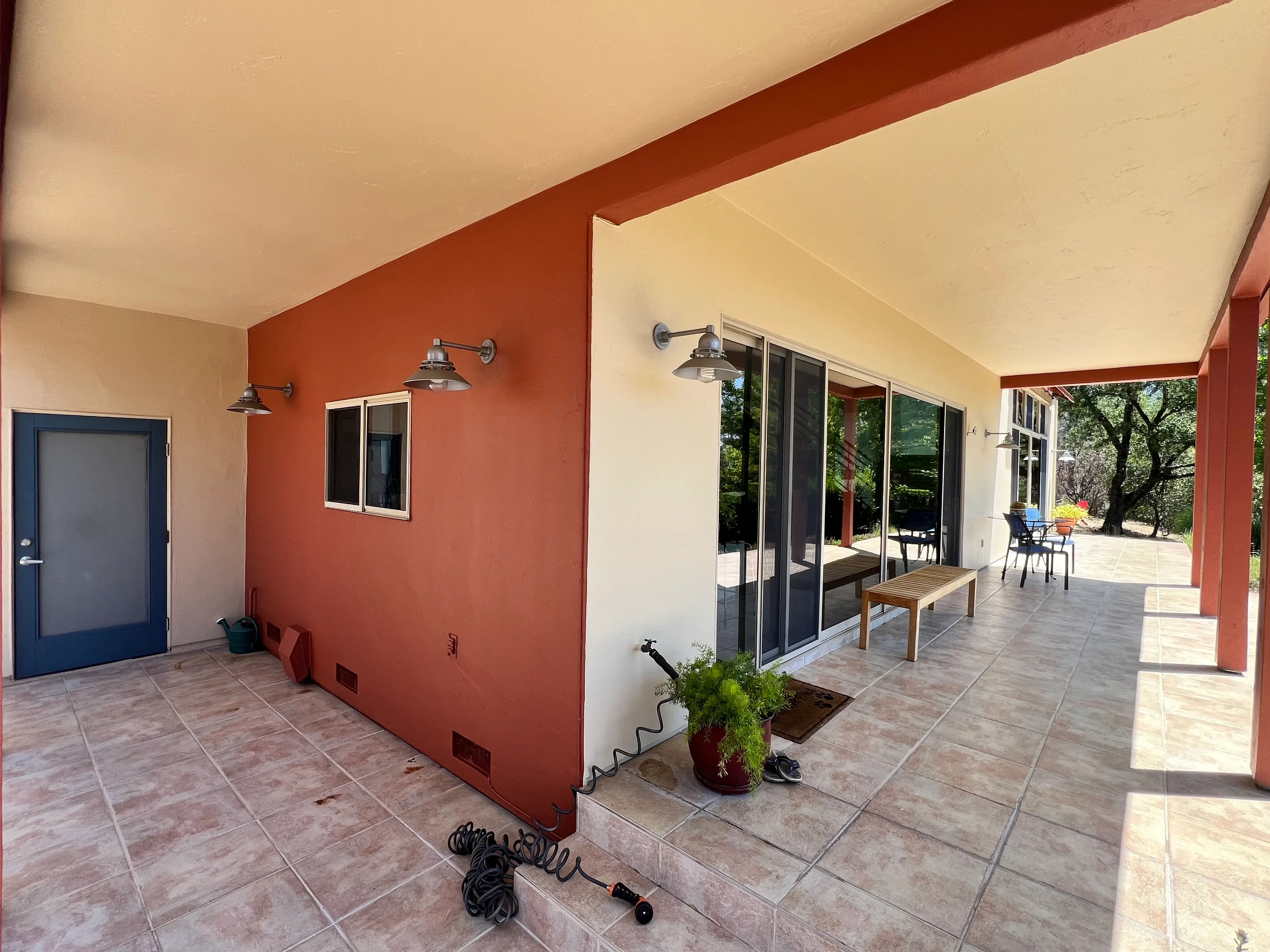 Rust-red accent wall with cream ceiling and beige trim in covered patio with sliding glass doors
