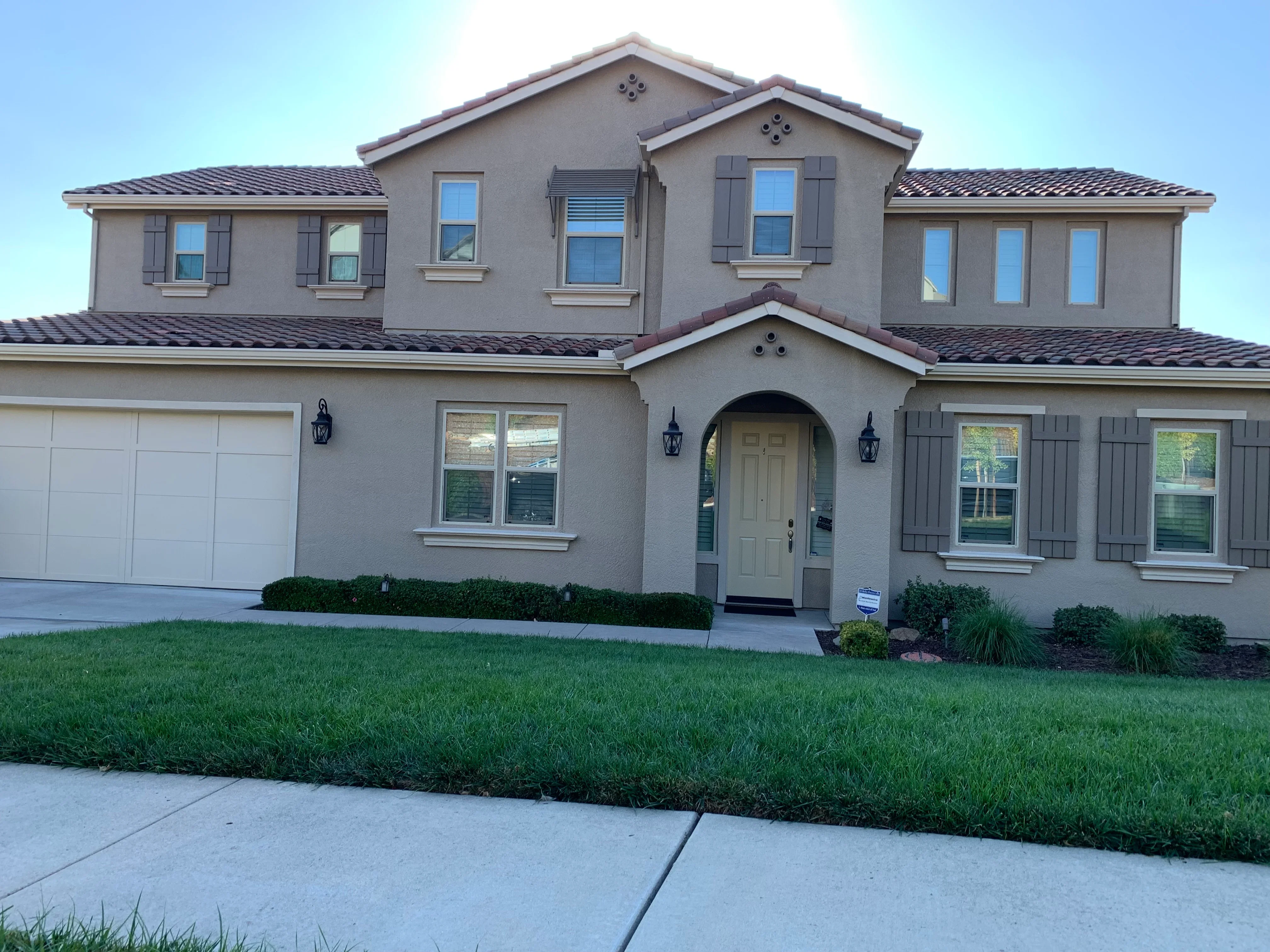 Two-story stucco home with taupe exterior paint, gray shutters, and white trim