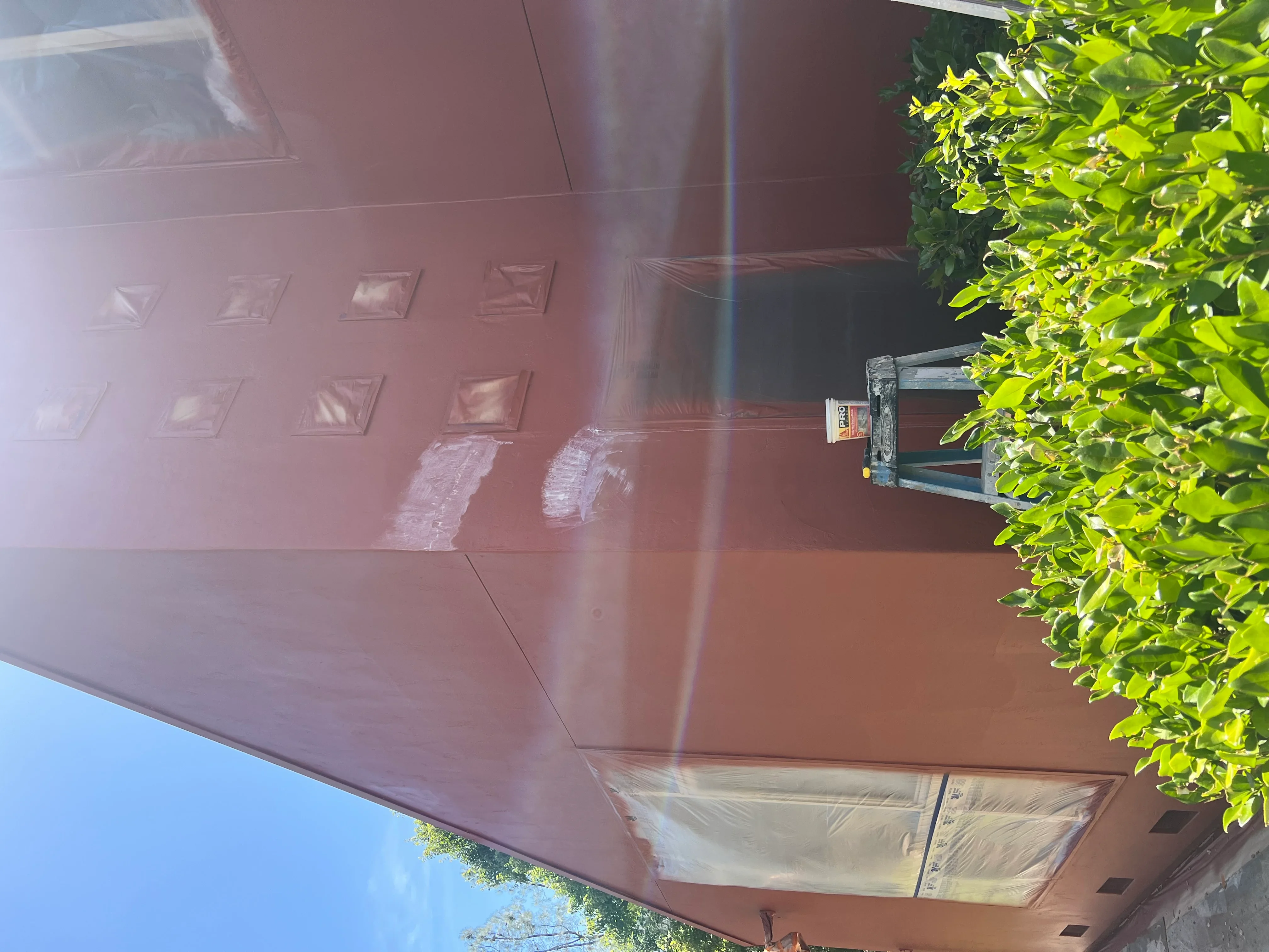 Mauve garage door with eight panels and fresh paint application in progress