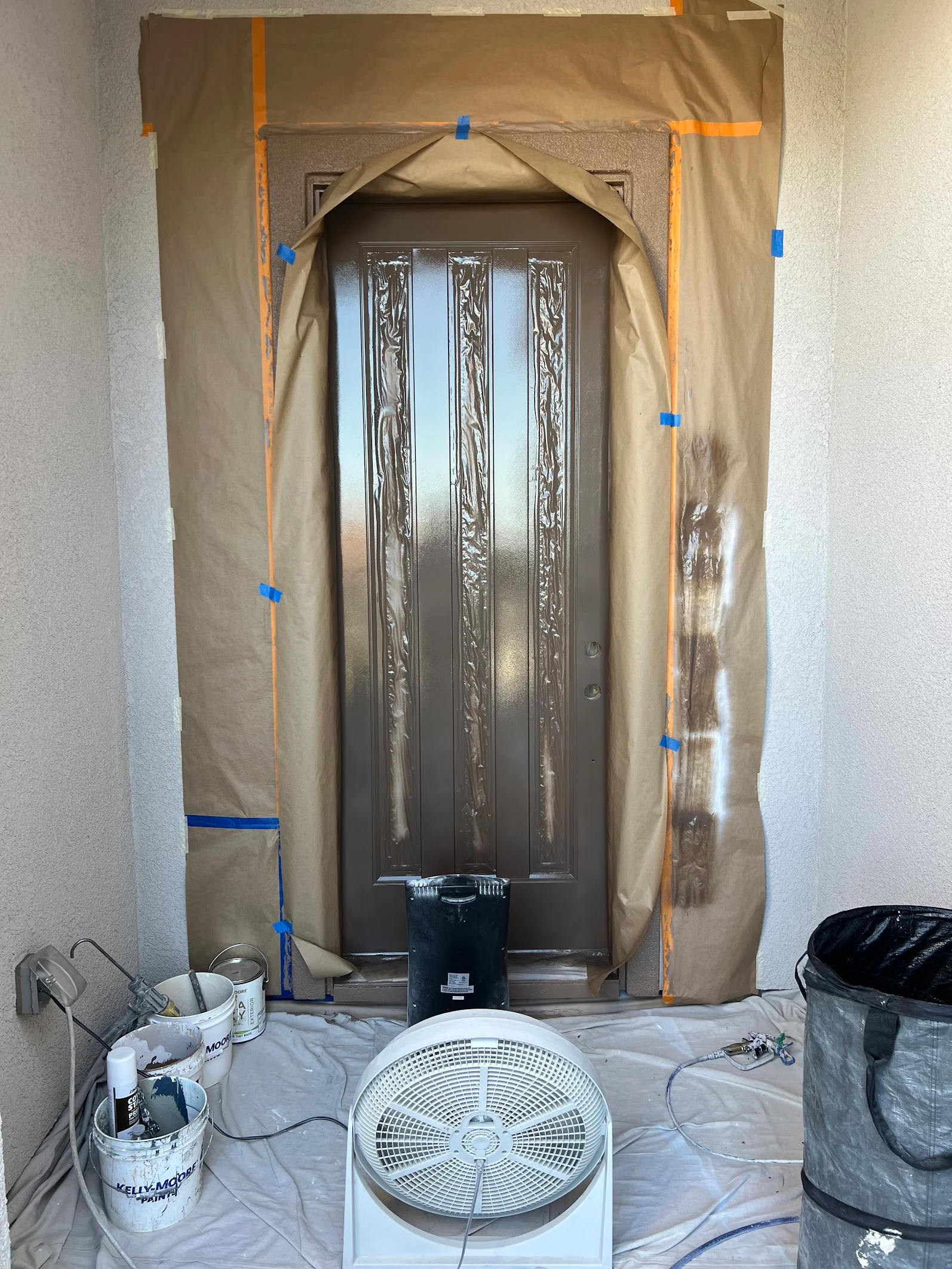 Ornate wood grain door masked with plastic sheeting and drop cloths for painting preparation