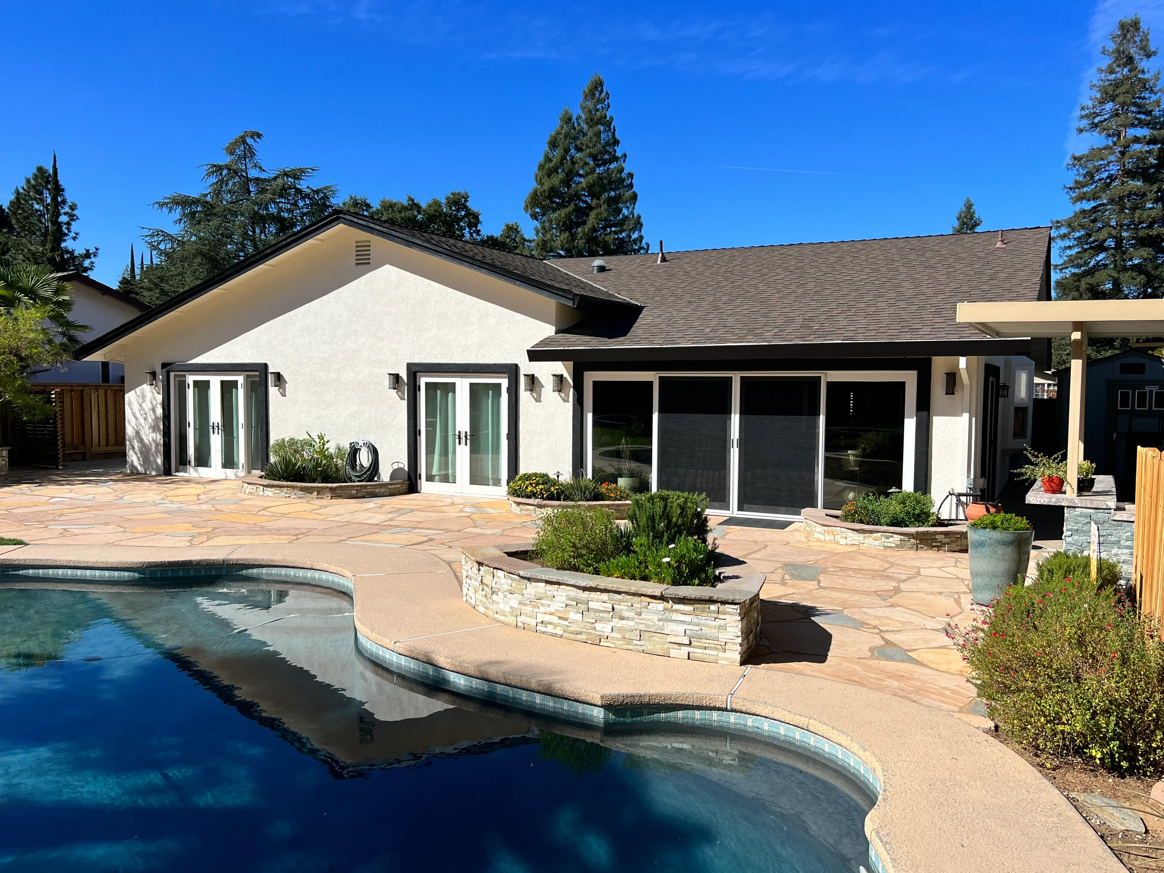 White stucco house with black-trimmed doors and windows overlooking pool patio