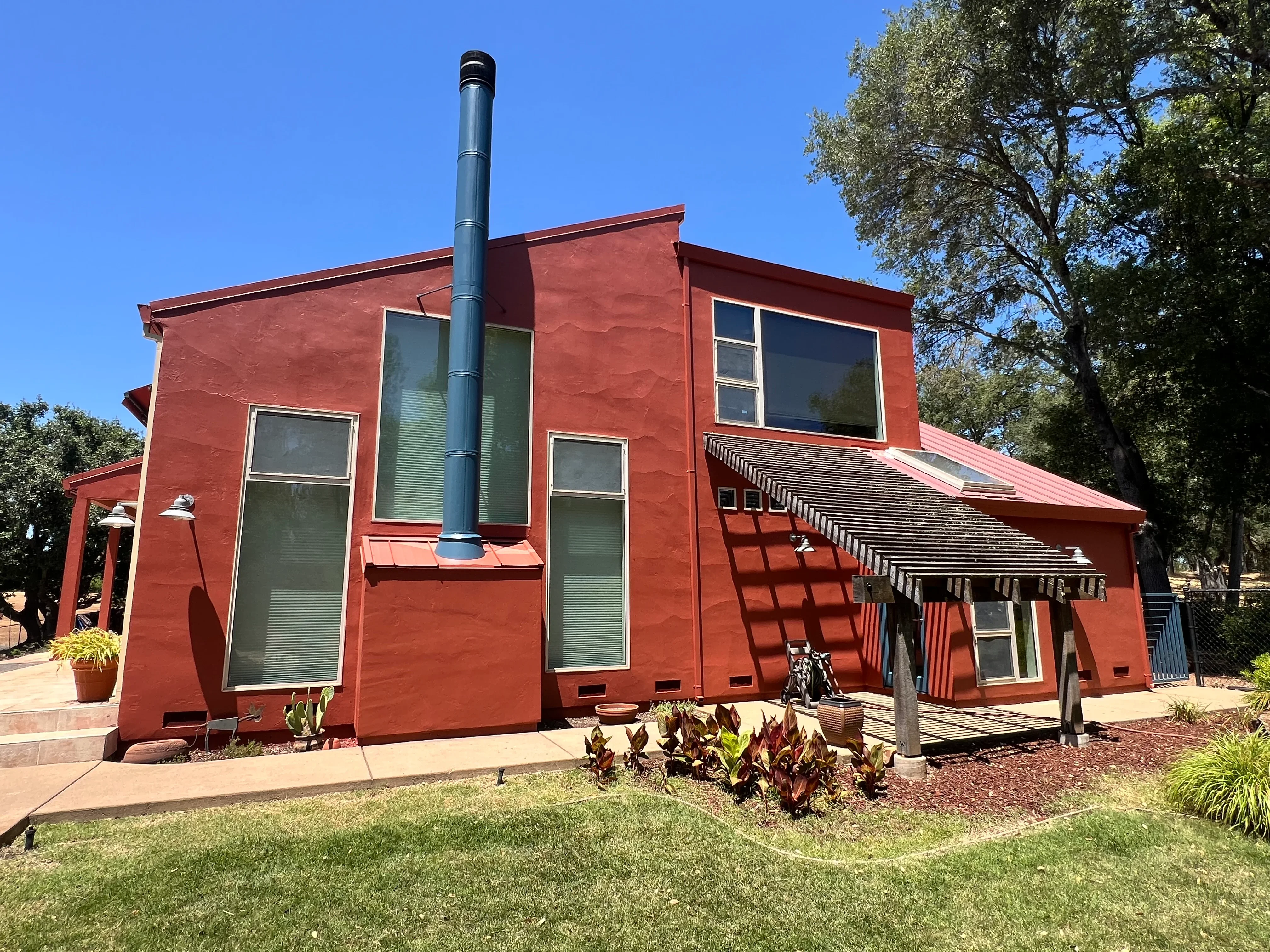 Red stucco house with green windows and metal awning in El Dorado Hills