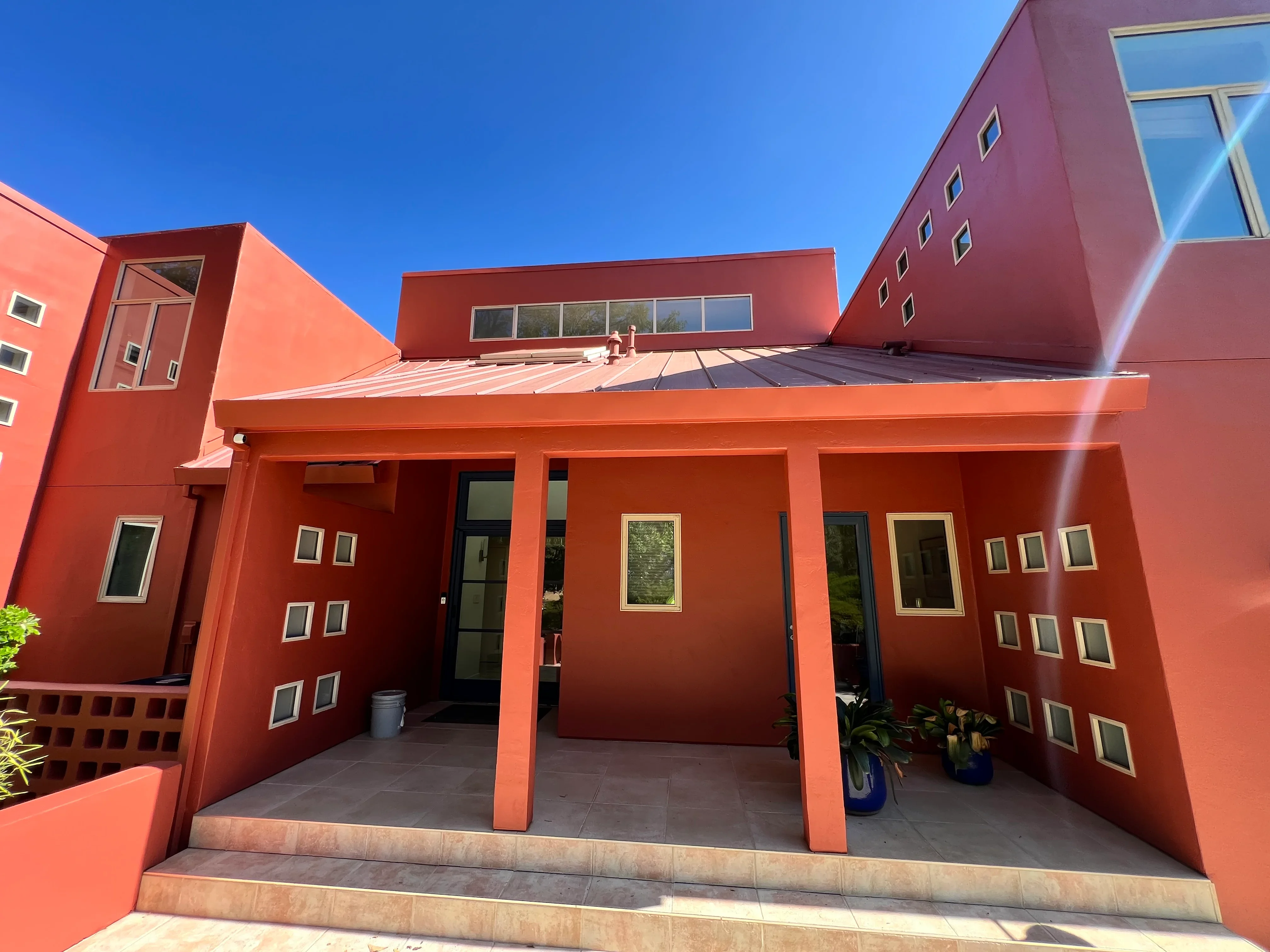 Modern home with rust-orange exterior paint and white-trimmed windows under clear blue sky