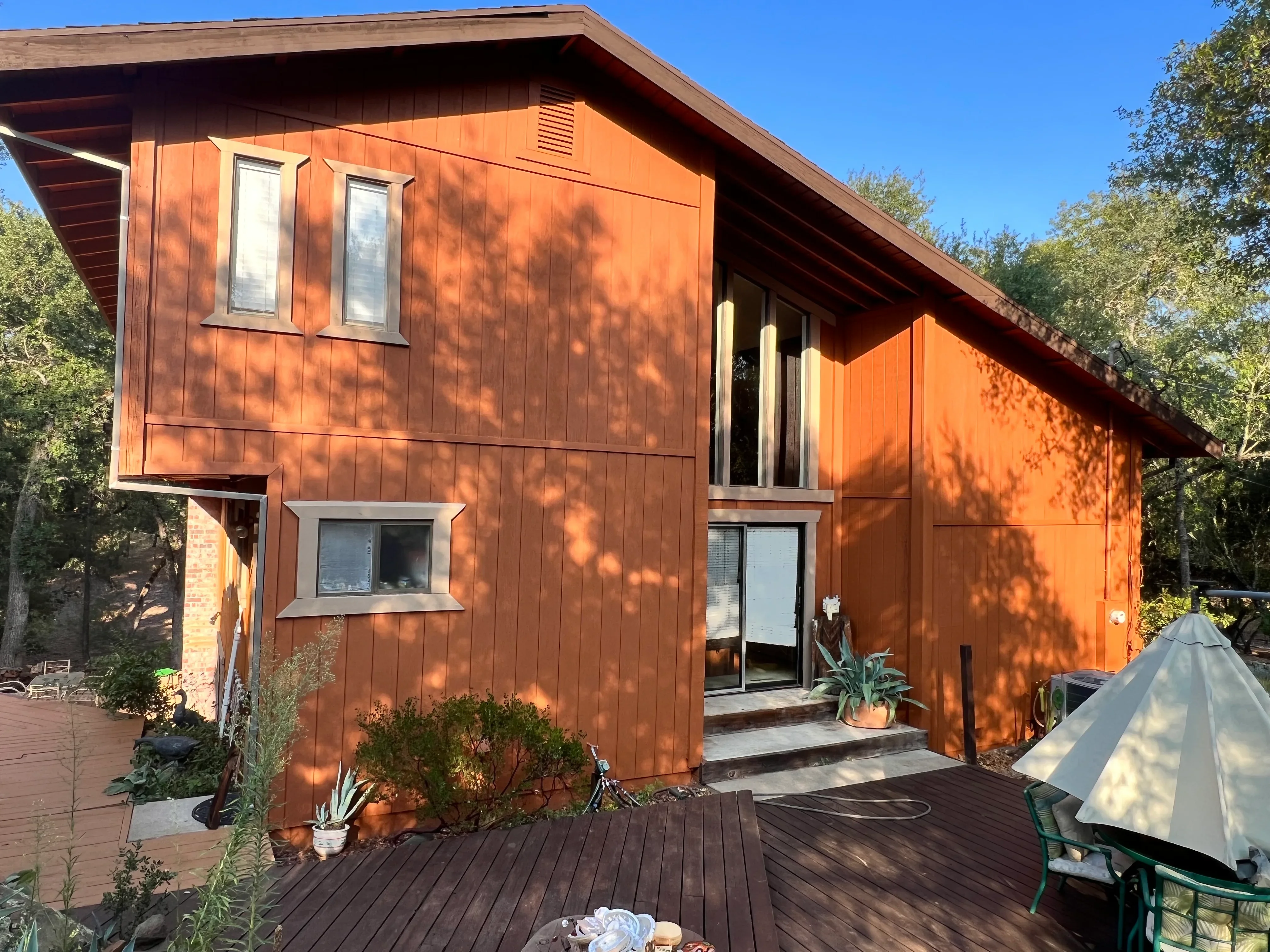 Orange modern home with vertical siding, painted exterior, deck, and landscaping