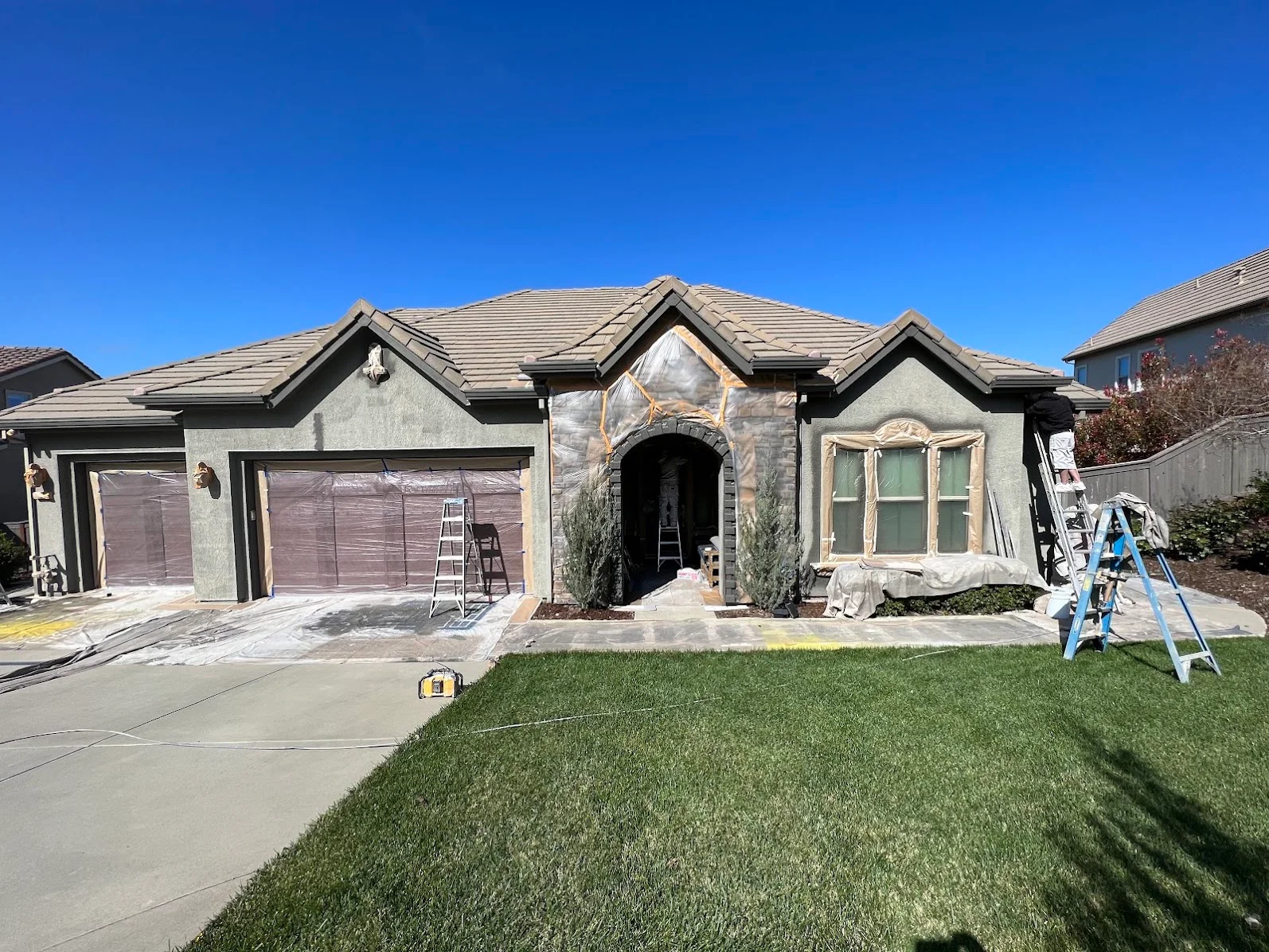 Stucco and stone house exterior with fresh paint, protective coverings on windows and entryway