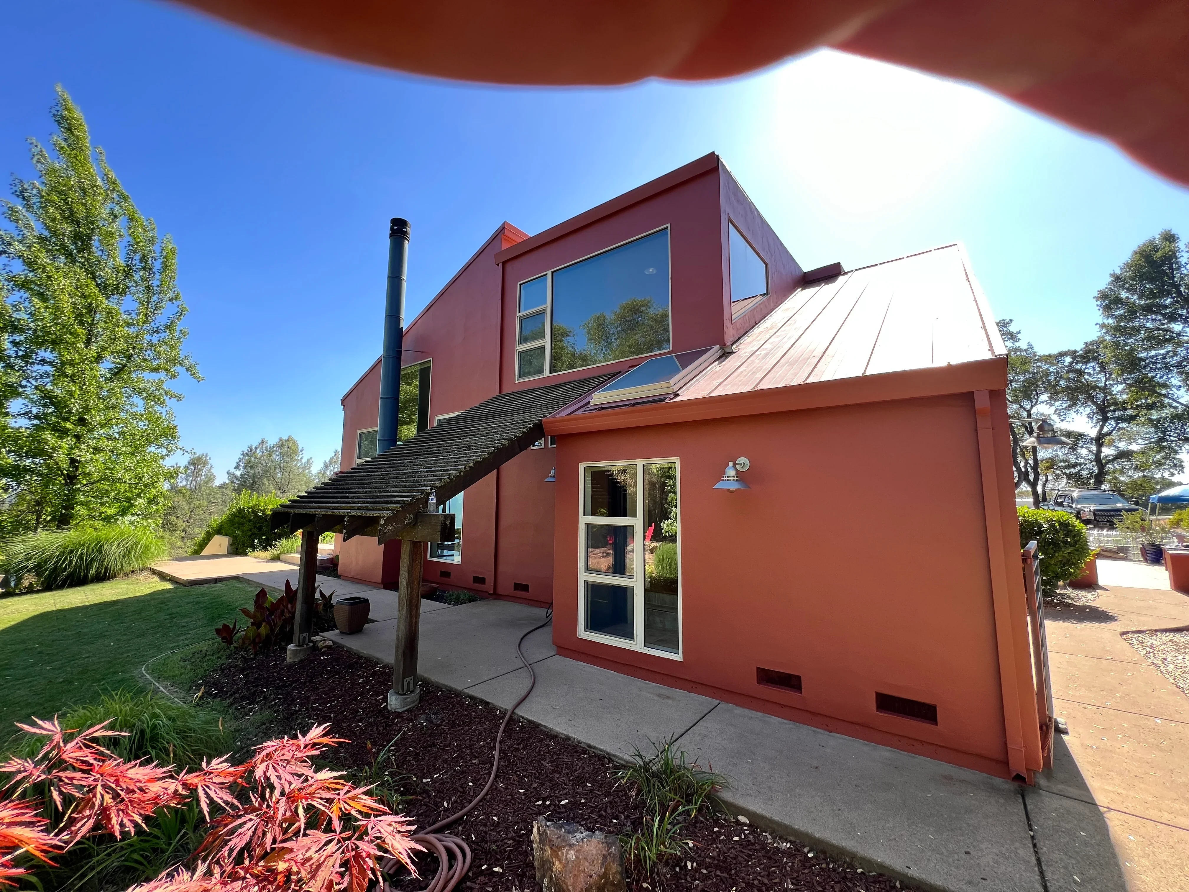 Modern rust-red painted home with white metal roof and large windows in El Dorado Hills