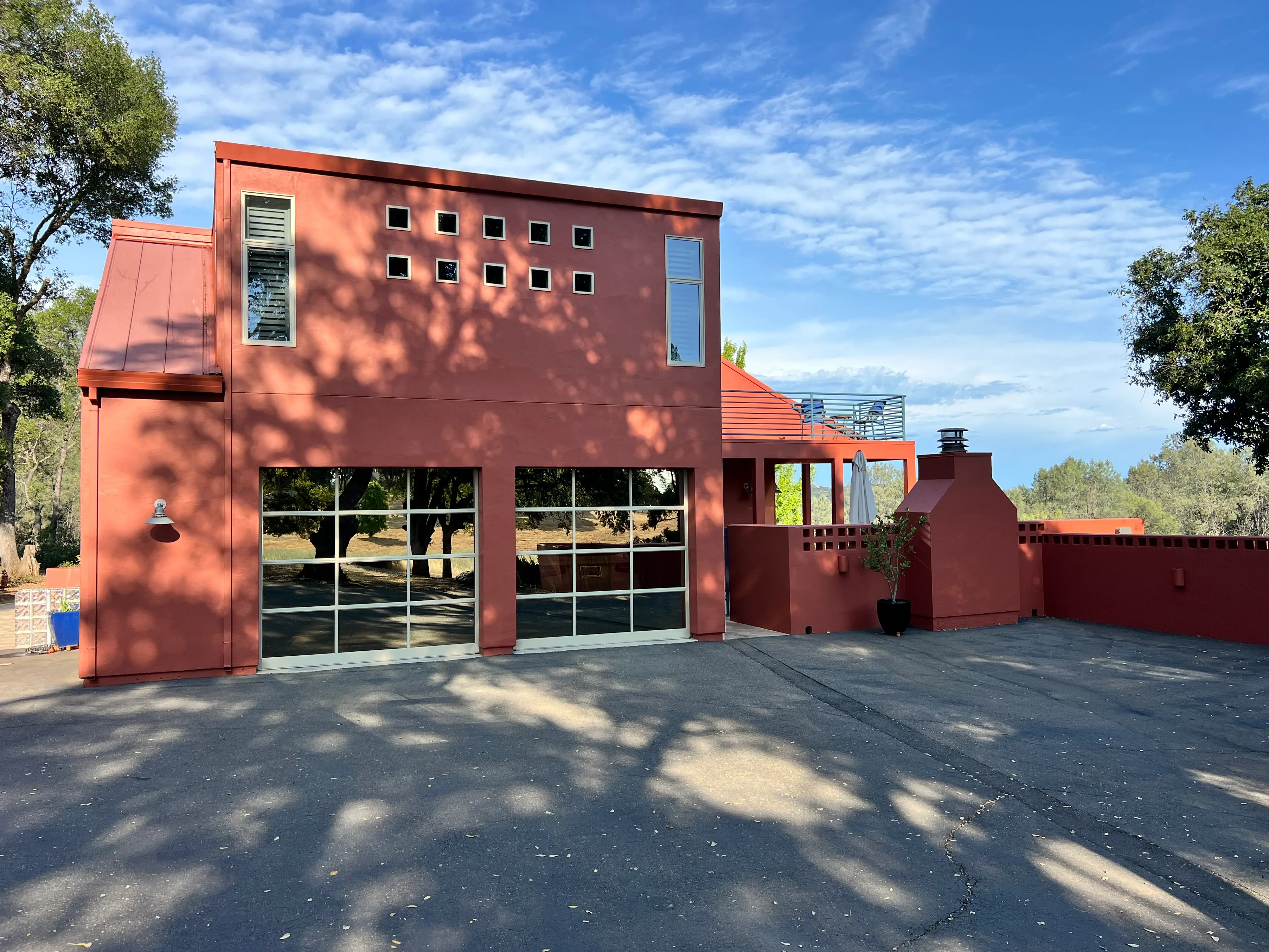Modern rust-red painted residential home with metal siding and large garage doors
