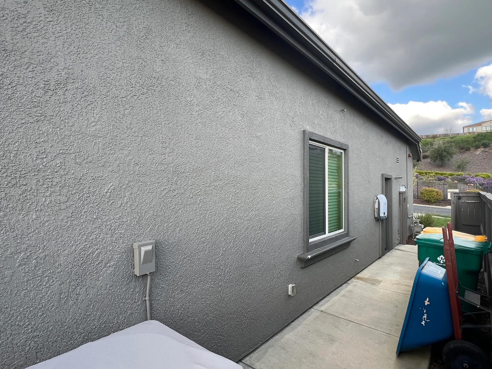 Gray textured render exterior wall with dark trim, window frame, and painted finish